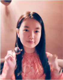 Portrait of Wing Pang smiling wearing a pink dress while holding a spoon.